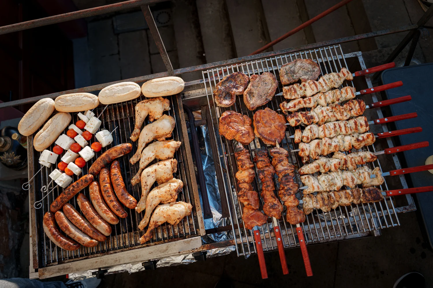 Königliche Schlossgastronomie – Dieses Bild zeigt einen großen Außengrill, gefüllt mit verschiedenen Grillspeisen.