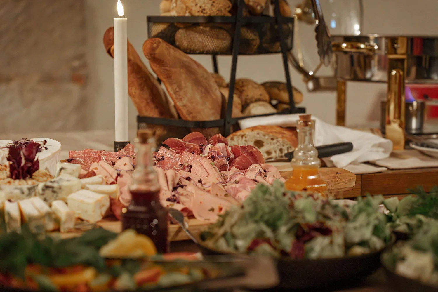 Königliche Schlossgastronomie – Das Bild zeigt ein Buffet mit einer Vielzahl von Gerichten, darunter warme Speisen in Warmhaltebehältern, frische Salate und eine Platte mit verschiedenen Fleisch- und Käsesorten.