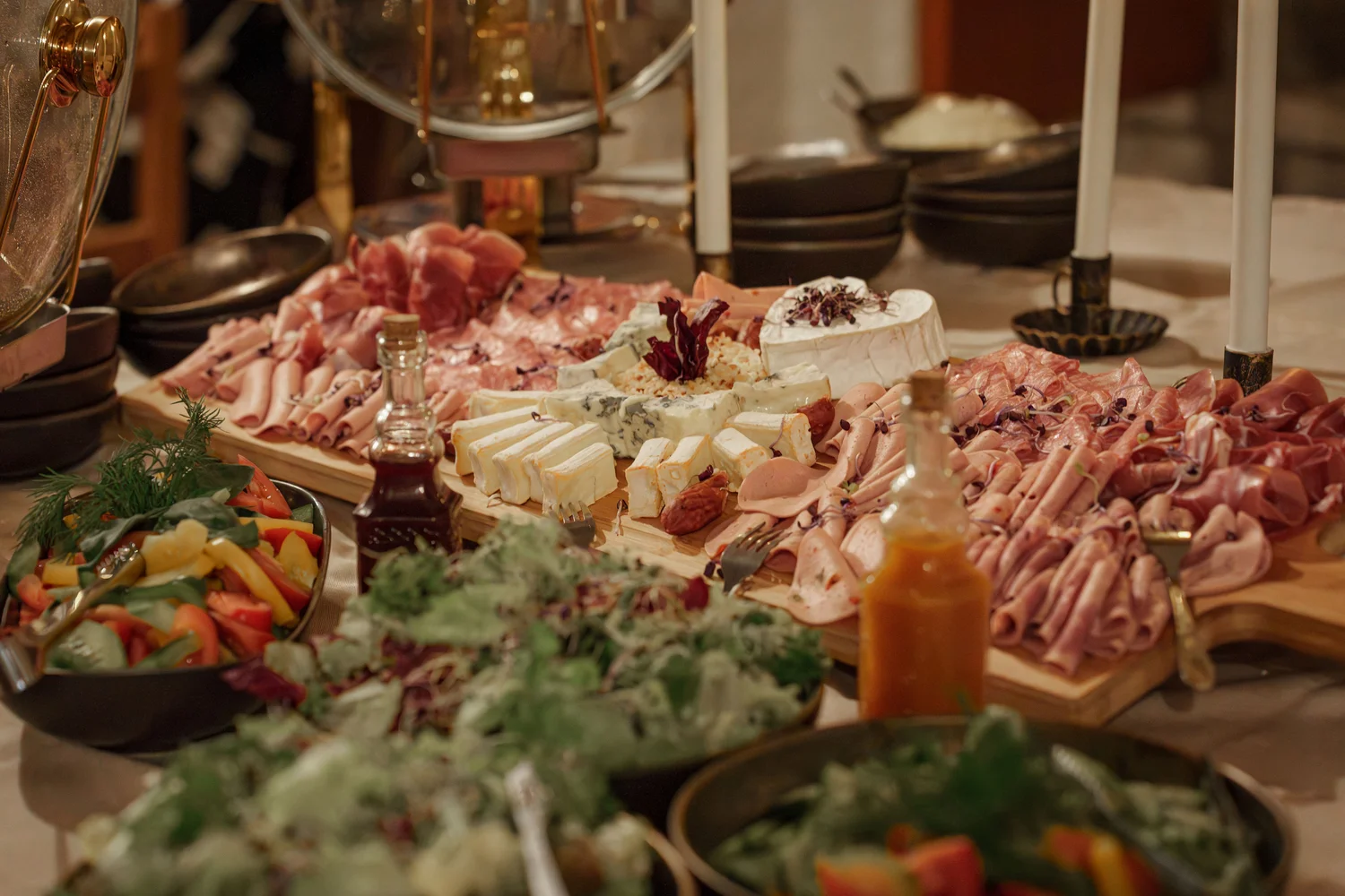 Königliche Schlossgastronomie – Das Bild zeigt ein Buffet mit einer Vielzahl von Gerichten, darunter warme Speisen in Warmhaltebehältern, frische Salate und eine Platte mit verschiedenen Fleisch- und Käsesorten.